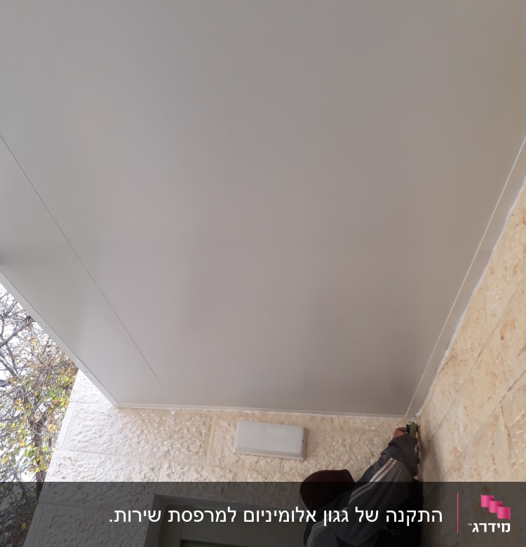 אדם מתקין תקרה מאלומיניום עם כלי עבודה